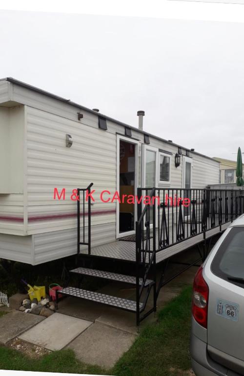 a mobile home with a porch and stairs at Beautiful 6 birth caravan in Ingoldmells
