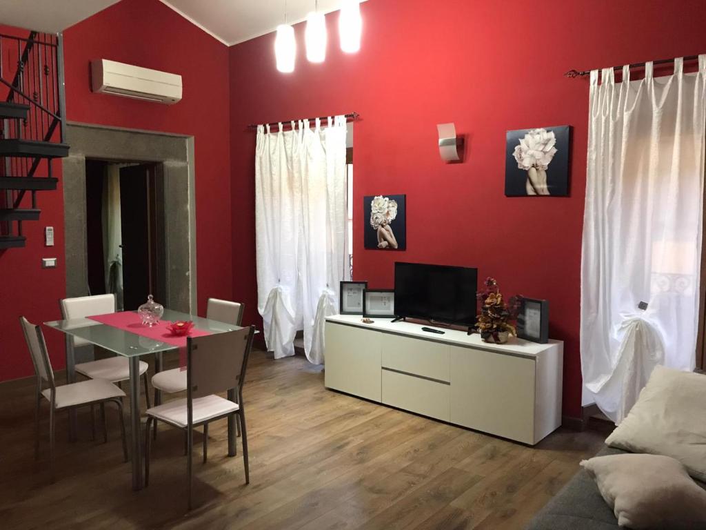 a living room with red walls and a table with a television at Civico 78 in Montefiascone