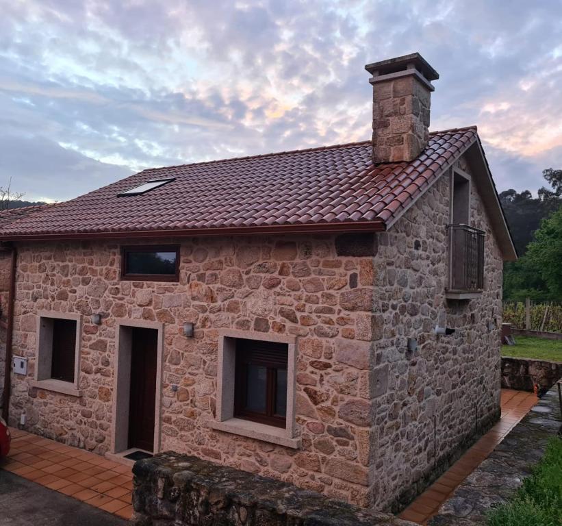 una casa in pietra con un camino sopra di Casa turística a Ardiña a Caldas de Reis