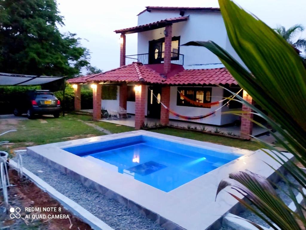 a villa with a swimming pool in front of a house at Casa Campo Emaus in Caucasia