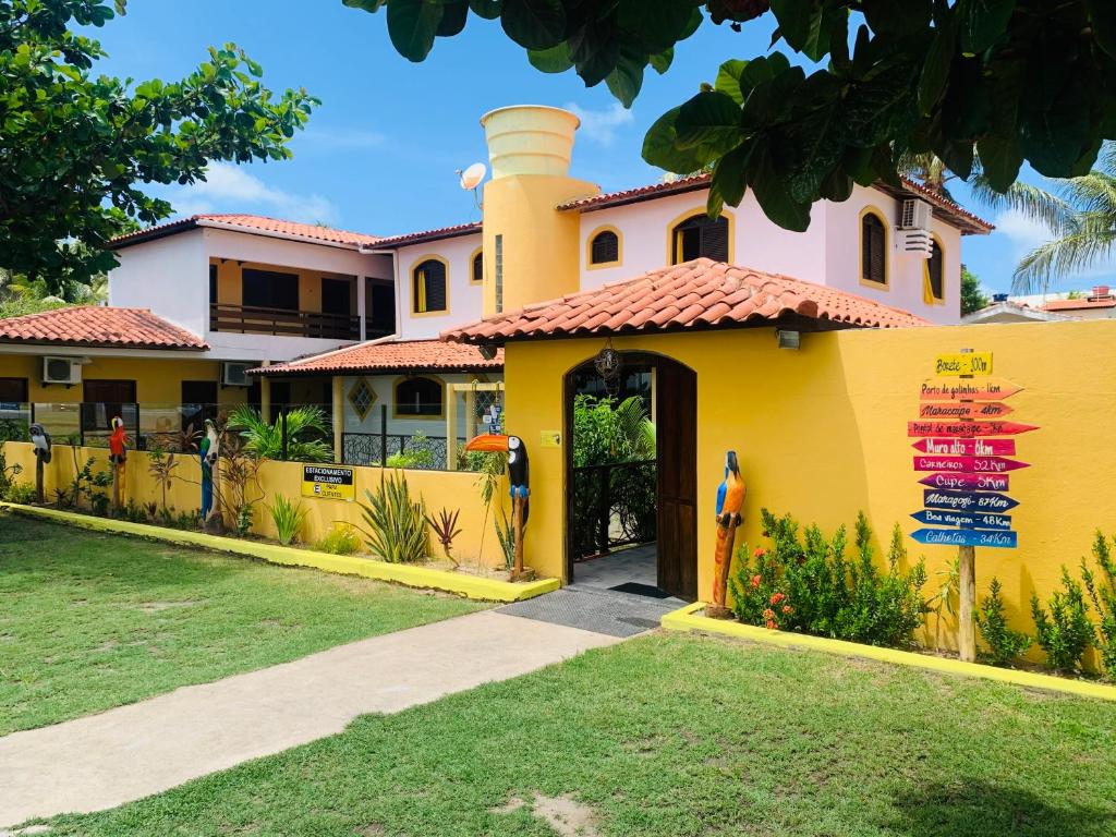 una casa amarilla con un cartel delante en Pousada Uba-Rio Porto de Galinhas, en Porto de Galinhas