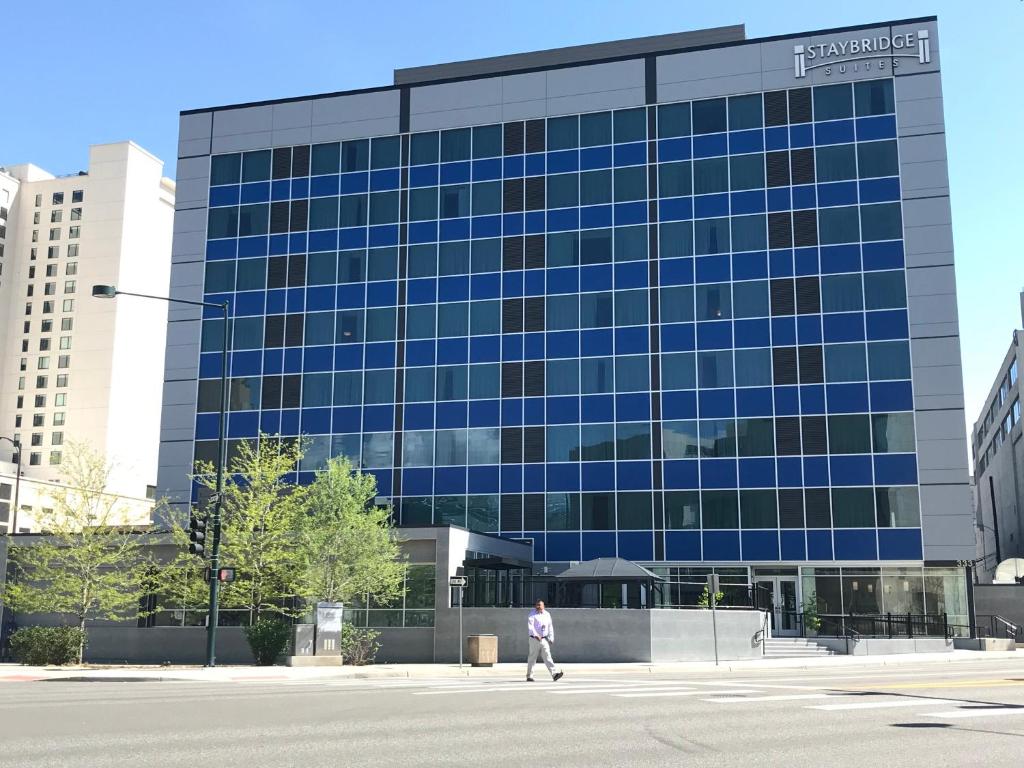 una persona caminando frente a un gran edificio de cristal en Staybridge Suites Denver Downtown, an IHG Hotel, en Denver