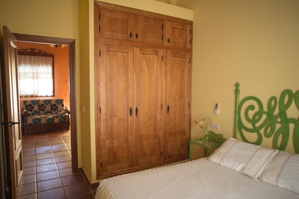 a bedroom with a wooden closet and a bed at Apartamentos Rurales Arco de Trajano in Alcántara