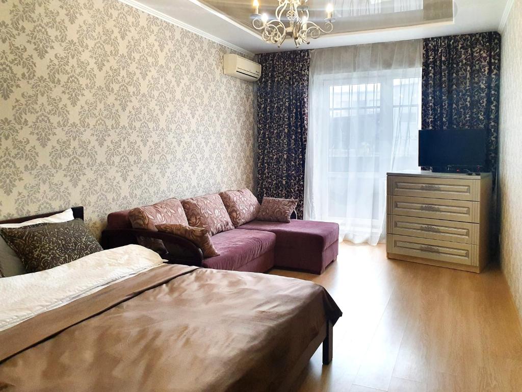 uma sala de estar com uma cama, um sofá e uma televisão em Lux Apartament Dacha em Kharkov