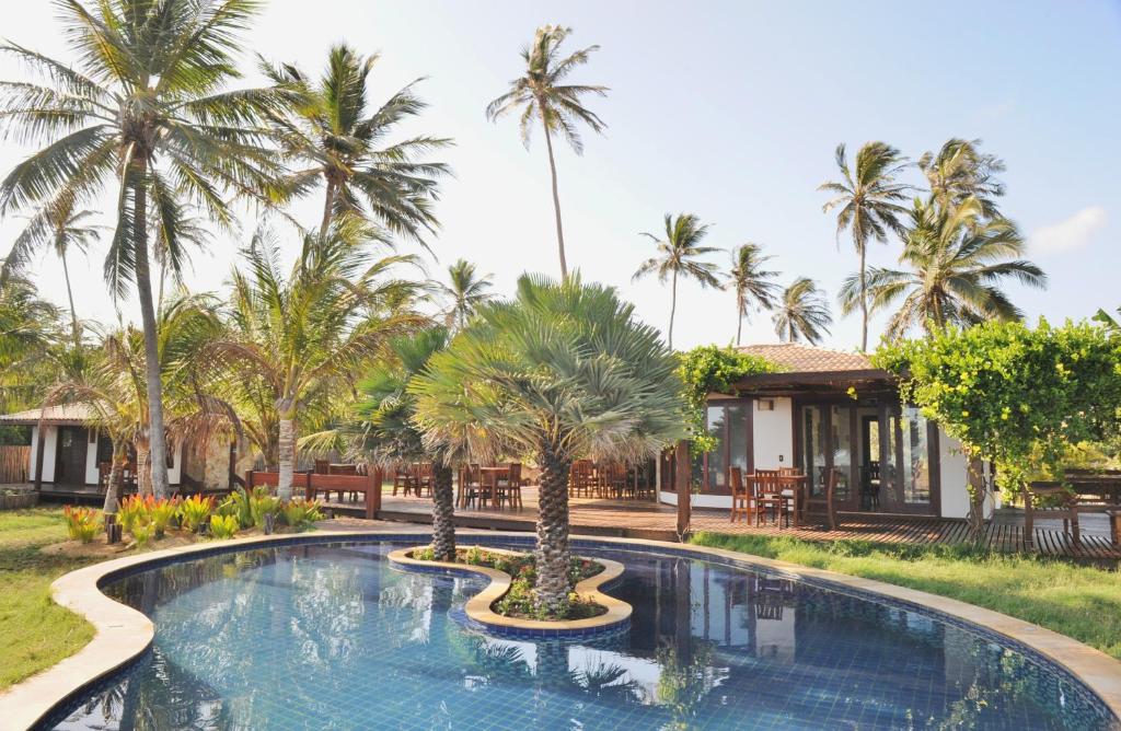 a pool at a resort with palm trees at Casa Della in Luis Correia