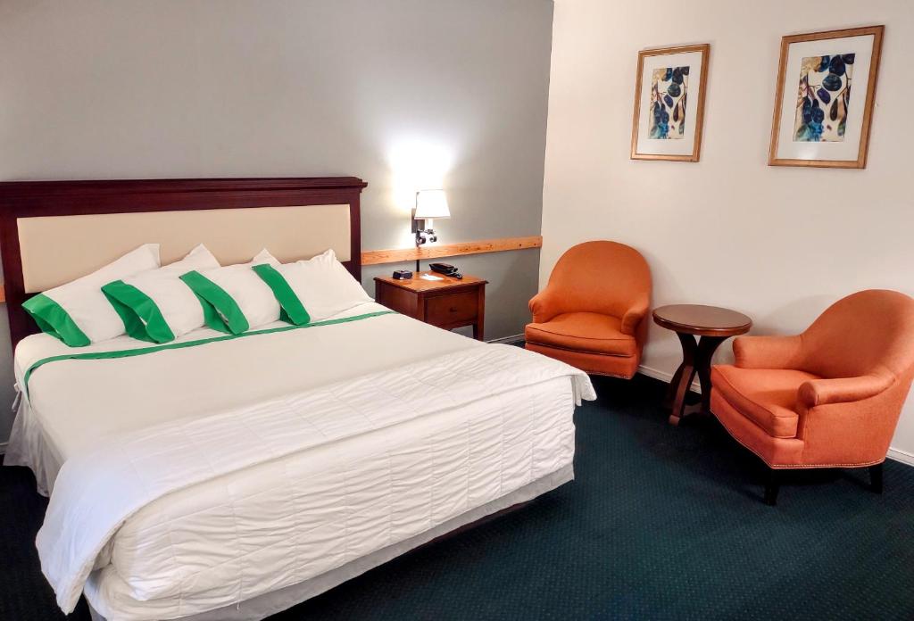 Habitación de hotel con 1 cama y 2 sillas de color naranja en GuestHouse Inn Enumclaw, en Enumclaw