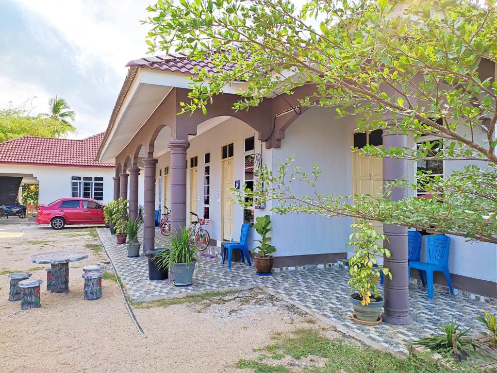 Desa Besut Inn في كامبونغ كوالا بيسوت: منزل مع شرفة وسيارة حمراء متوقفة