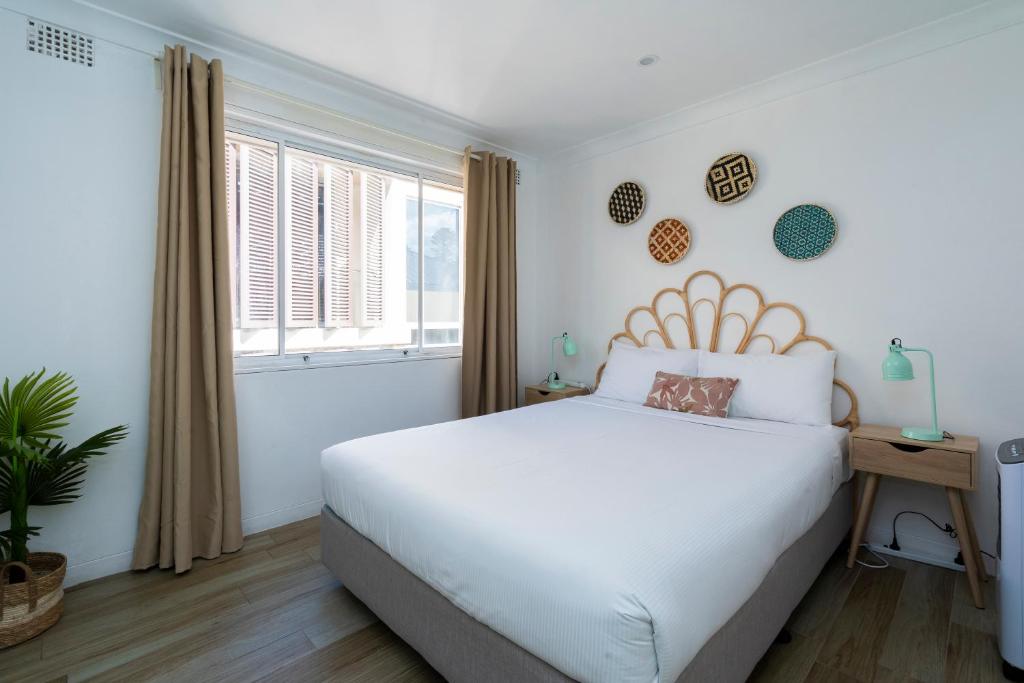 Manly Beachfront Apartment في سيدني: غرفة نوم بسرير ابيض ونافذة
