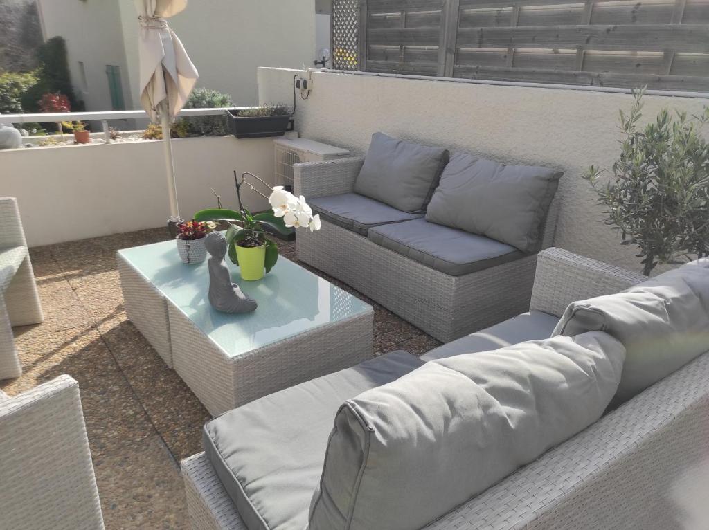 une terrasse avec des canapés et une table avec des fleurs dans l'établissement 2 pièces avec grande terrasse, à La Ciotat