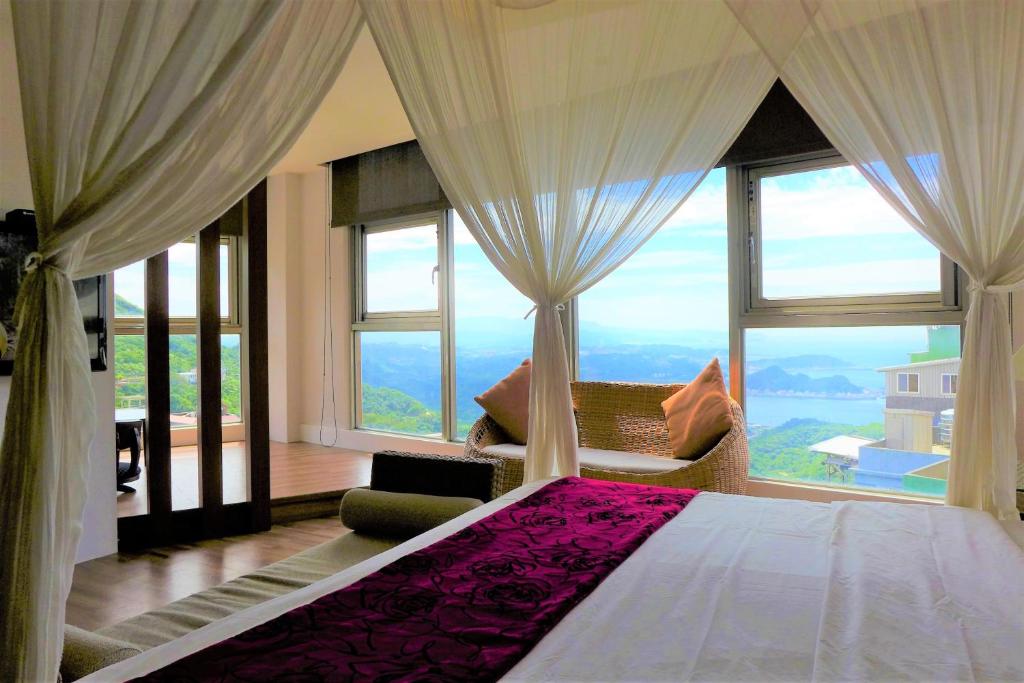 a bedroom with a bed with a large window at Chiu Chunt Dint B&B in Jiufen