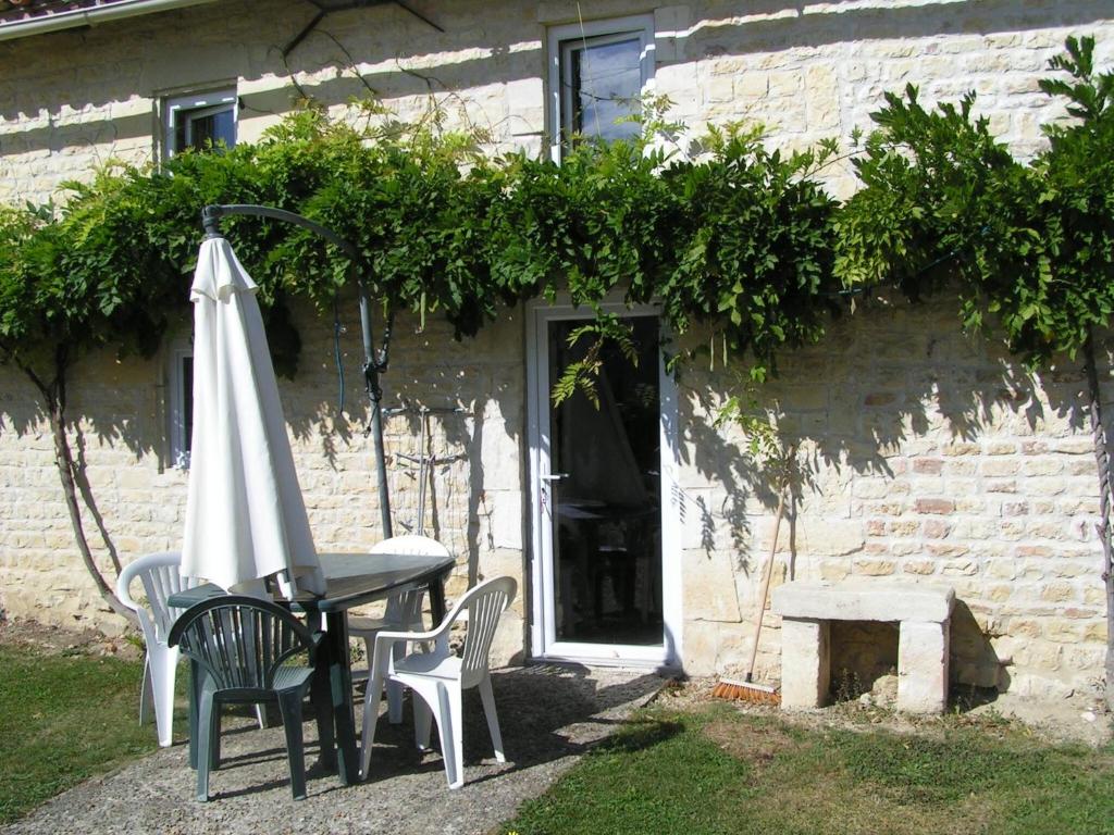 einen Tisch mit einem Sonnenschirm und Stühlen sowie einen Tisch mit einem Sonnenschirm in der Unterkunft Columba - Les Constellations in Doeuil-sur-le-Mignon