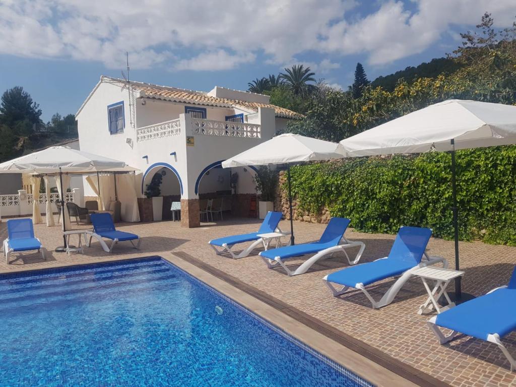 a pool with chairs and umbrellas next to a house at A867 - La Rodeta in Callosa de Ensarriá