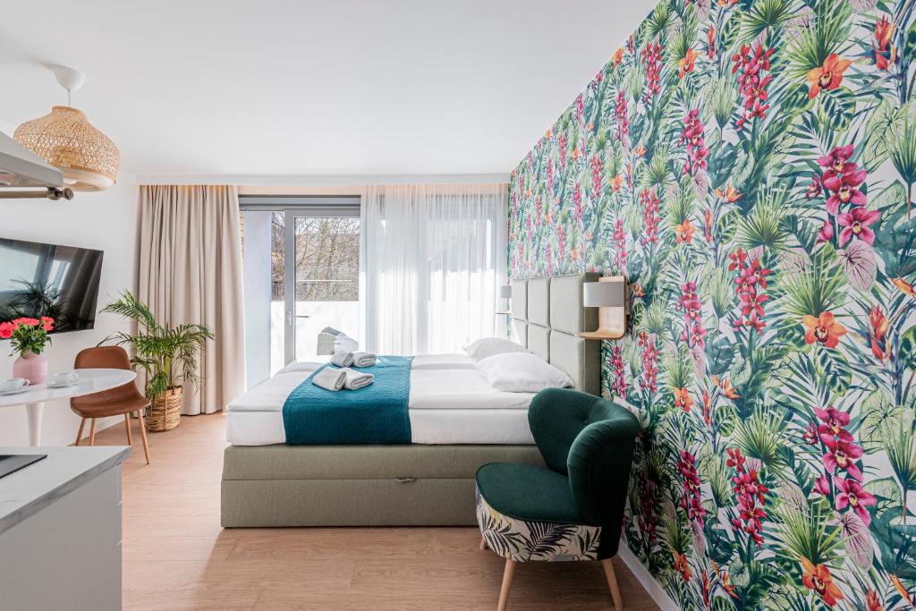ソポトにあるLapwing Residence Sopotのベッドと緑の椅子が備わるホテルルームです。