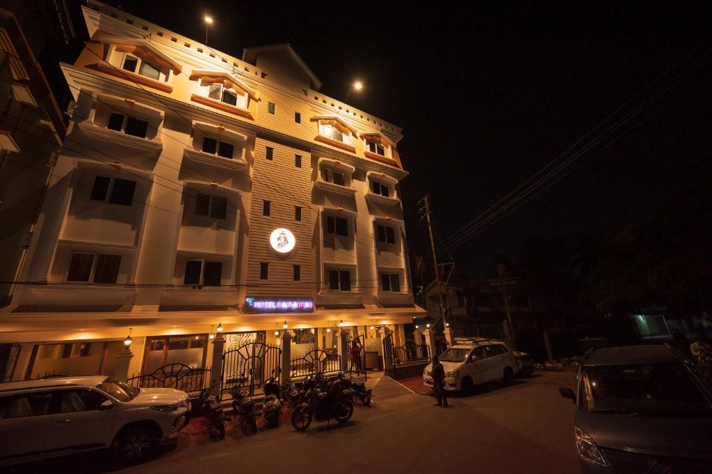 een gebouw waar 's nachts auto's voor geparkeerd staan bij Rajdarbar Hotel & Banquet, Siliguri in Siliguri