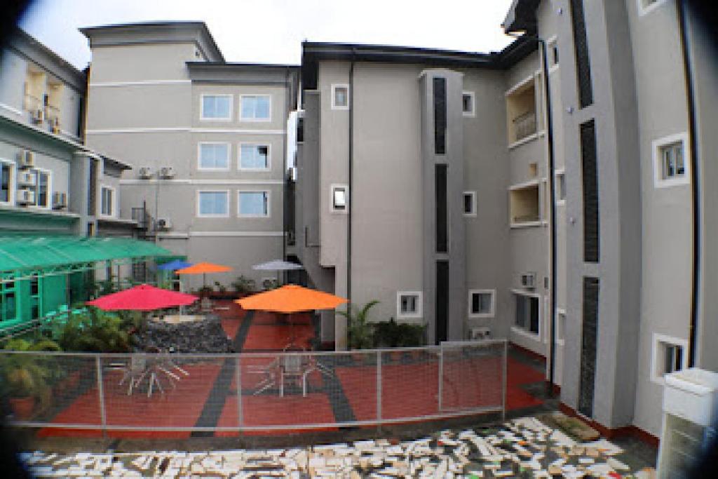 a view of a courtyard with tables and orange umbrellas at Room in Lodge - All Seasons Hotel-apartment in Owerri