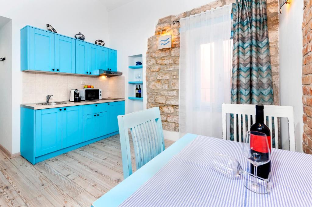 a kitchen with blue cabinets and a table with a bottle of wine at Apartments & Rooms La casa Barbaro in Rovinj