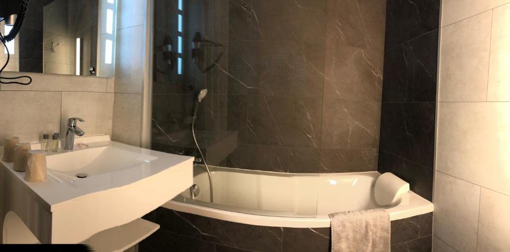 a bathroom with a sink and a bath tub at Cit'Hotel Atlantis in Royan