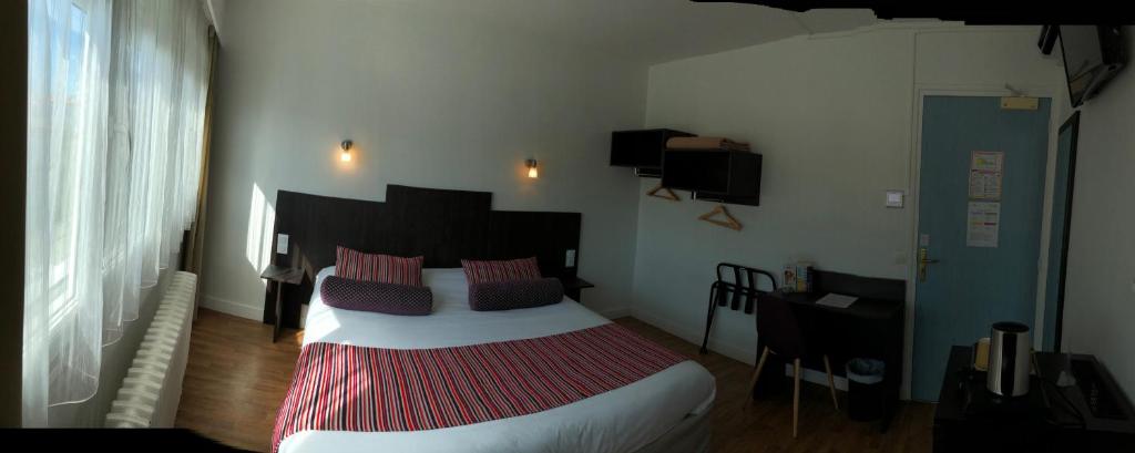 a bedroom with a large bed and a desk at Cit'Hotel Atlantis in Royan