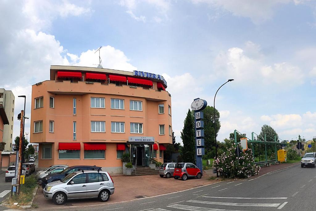 a building with cars parked in a parking lot at Hotel Riviera in Segrate