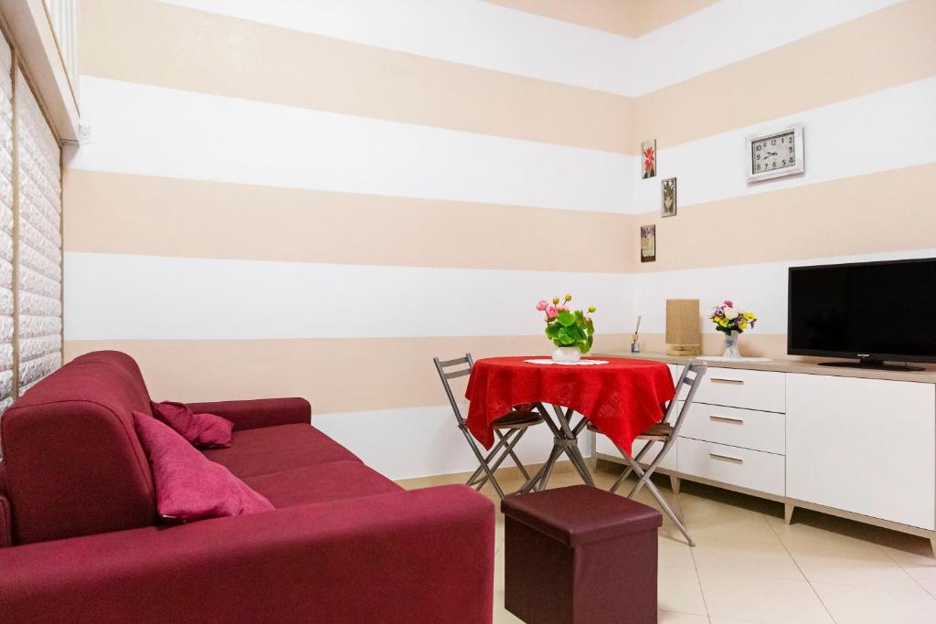 ein Wohnzimmer mit einem roten Sofa und einem Tisch in der Unterkunft CASABELLA in Grottaglie