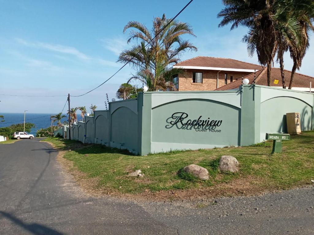 een hek aan de kant van een weg naast een huis bij Rockview Guest House in Port Edward