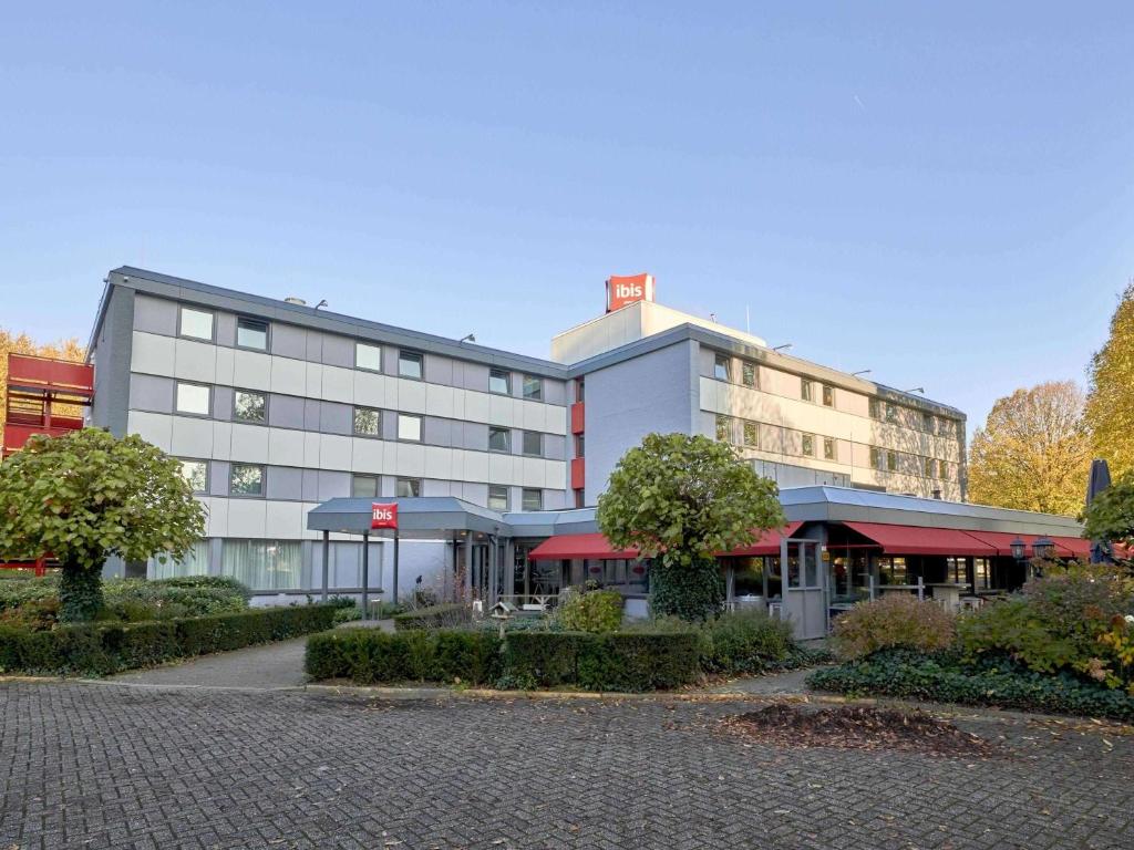 a large building with red awnings in front of it at ibis Tilburg in Tilburg