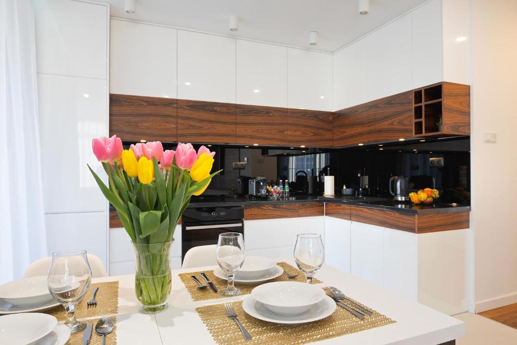 een witte keuken met een tafel met bloemen in een vaas bij Apartamenty Prestige Browar Lubicz Stare Miasto in Krakau