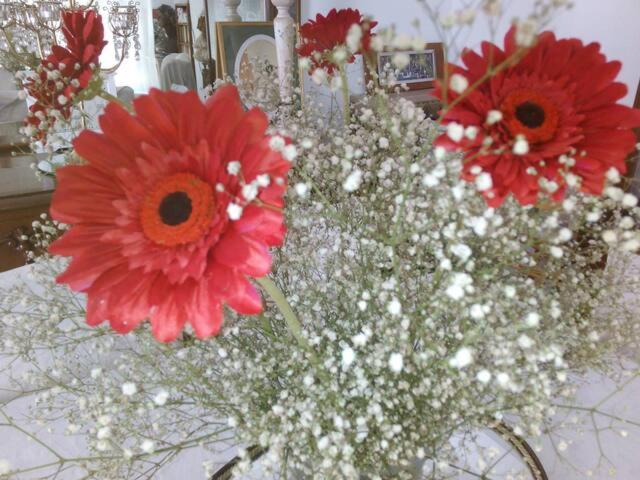 um vaso cheio de flores vermelhas sobre uma mesa em CHAMBRES D'HÔTES CHEZ CATHERINE A REUS chambre bord de mer avec salle de bains privée em Reus