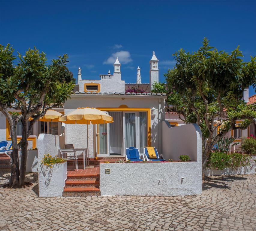 een huis met een patio met stoelen en een parasol bij Quinta Paraiso da Mia - 1 Bedroom Apartment in Luz