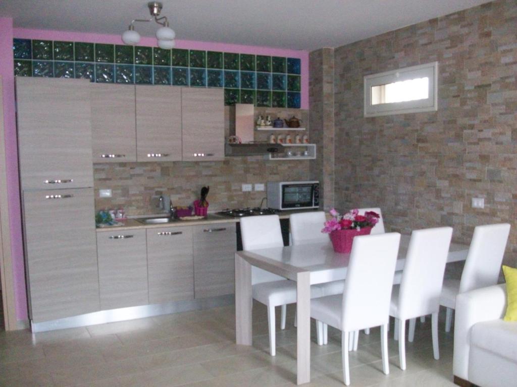 una cucina con tavolo bianco e sedie bianche di ColourHouse a Furci Siculo