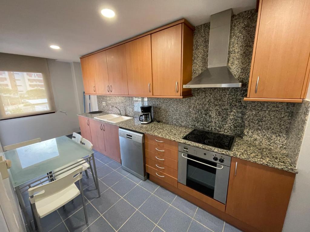 a kitchen with wooden cabinets and a counter top at SeaHomes Vacations, FENALS BEACH&CHIC, pk, top apartment full equipped in Lloret de Mar