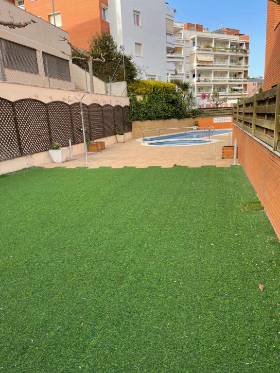 a yard of green grass next to a pool at SeaHomes Vacations, FENALS BEACH&CHIC, pk, top apartment full equipped in Lloret de Mar