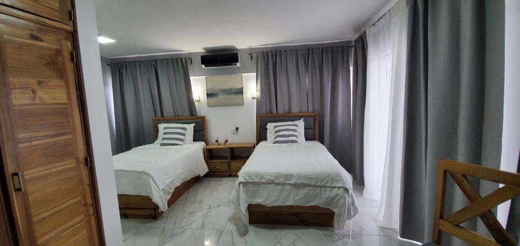 1 Schlafzimmer mit 2 Betten und einem Fenster mit Vorhängen in der Unterkunft Boca Grande Hotel Suites in Boca Chica
