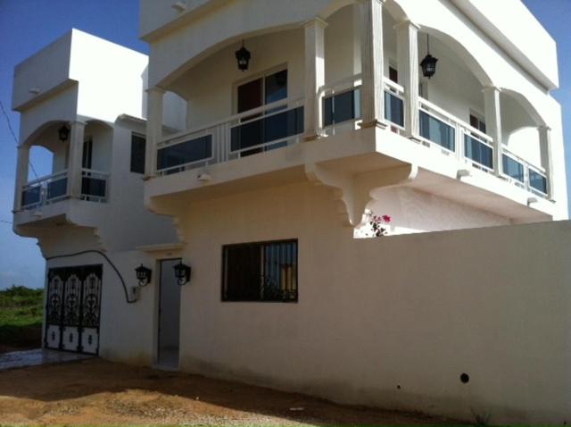 Una casa blanca con un balcón en el lateral. en Villa à Thiès avec piscine à 15mn de l'aéroport, en Thiès