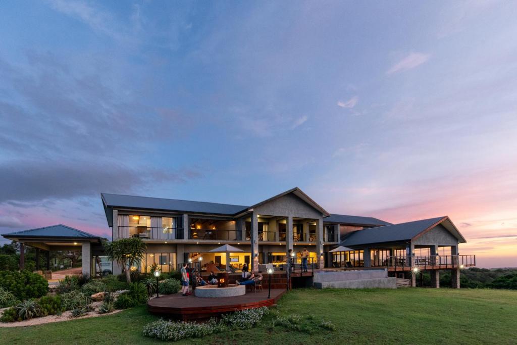 une grande maison avec des personnes assises à l'extérieur au crépuscule dans l'établissement Intle Boutique Hotel, à Jeffreys Bay