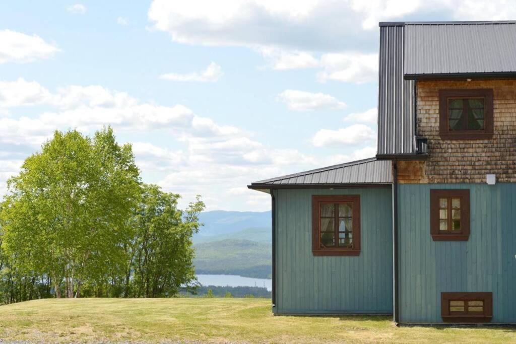 a house on top of a field with a lake at Le Chic-Boisé - SPA, Vue, Grandiose in La Malbaie
