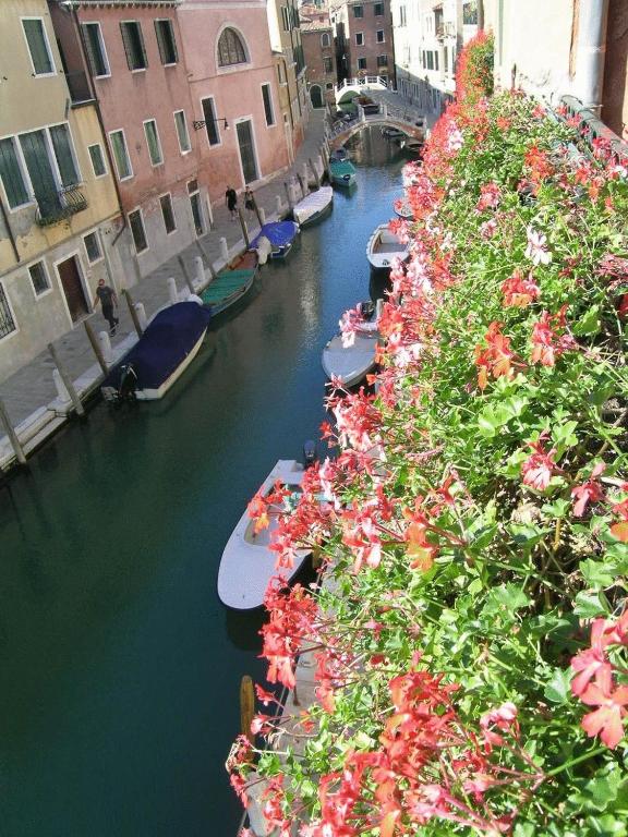 a group of boats in a canal with flowers at Antica Locanda Montin in Venice