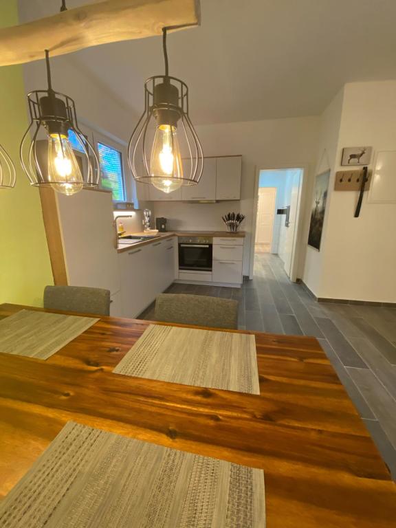 a kitchen and living room with a wooden table and lights at AlbLounge VIP Appartement in Neuffen