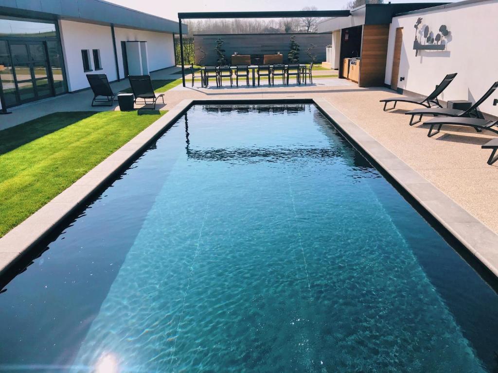 una piscina con agua azul en un patio trasero en 5-sterren Landhuis met zwembad en jacuzzi en Ypres