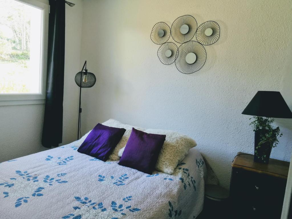 Un dormitorio con una cama con almohadas moradas y una ventana en FLOREVA Proche plage et thalasso, en Concarneau