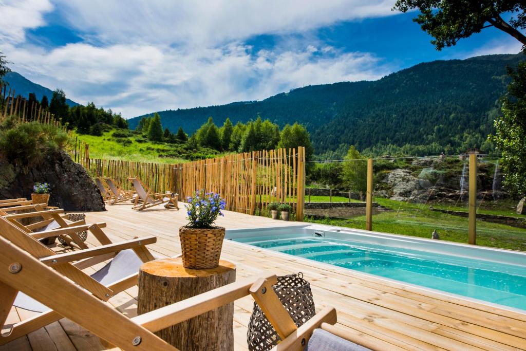 a deck with a pool and chairs and a fence at Mountain Hostel Tarter in El Tarter