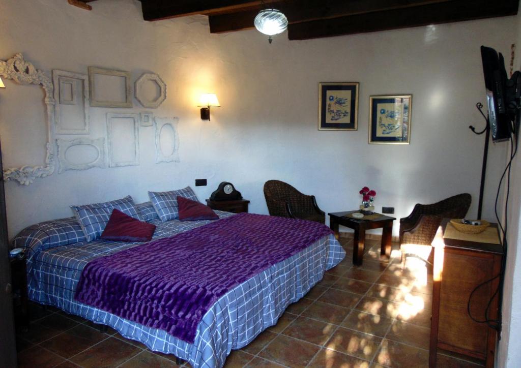1 dormitorio con cama morada y mesa en Casas Rurales Lagunas de Ruidera - Piscina, en Ossa de Montiel