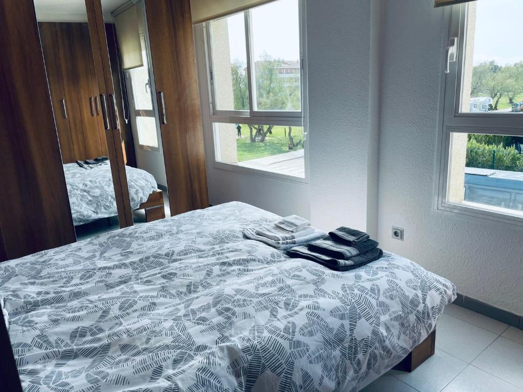 1 dormitorio con 1 cama con edredón blanco y ventanas en APARTAMENT ILLA MAR D´OR L`ESTARTIT, en L'Estartit