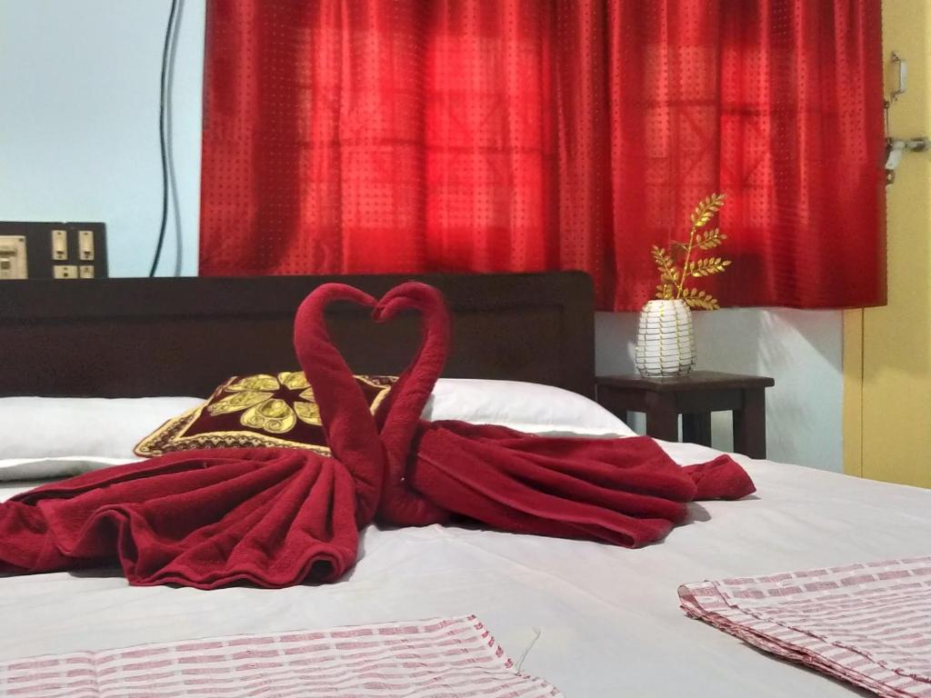 - une couverture rouge sur un lit avec un rideau rouge dans l'établissement Ahobilaa Homestay, à Tiruchirappalli