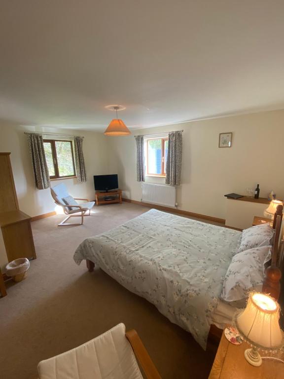 a bedroom with a large bed and a chair at Laurel Bank in Abbey-Cwmhir