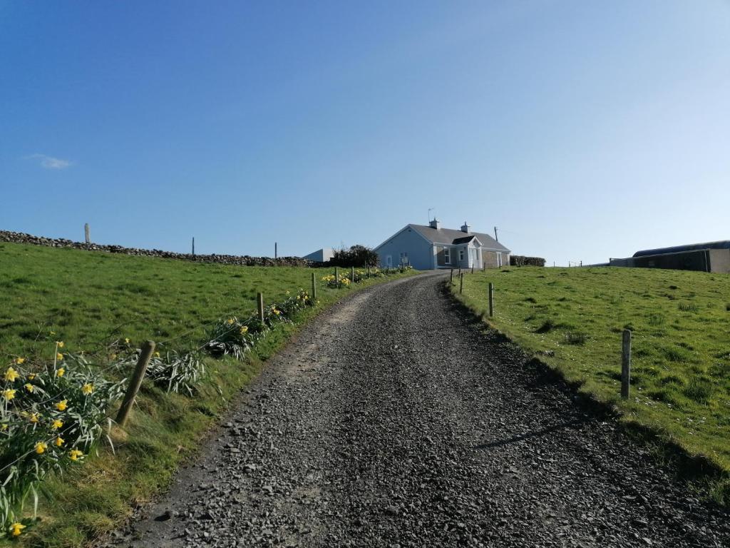 a dirt road in a field with a house in the background at Atlantic Way Farmhouse in Lahinch