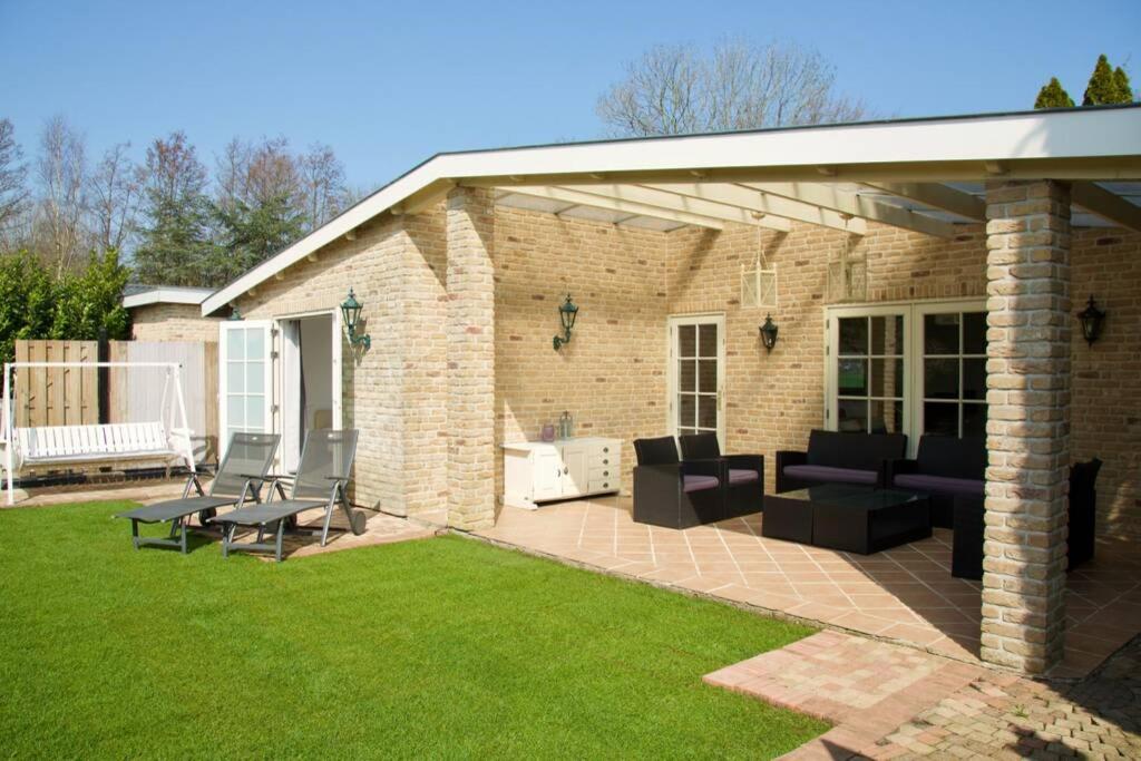 a patio with couches and chairs on a lawn at Spaanse Bungalow nabij Amsterdam with Sauna and steam sauna in Vijfhuizen