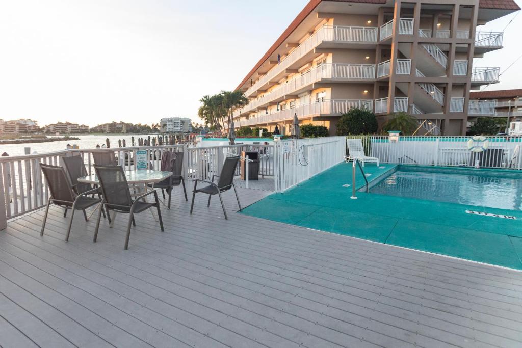 a deck with a table and chairs next to a swimming pool at The BoatHouse in Marco Island