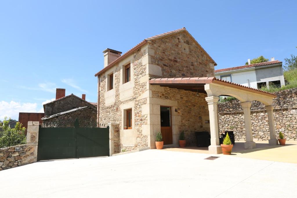 a stone house with a gate and a stone wall at Casal Rivas in Muxia