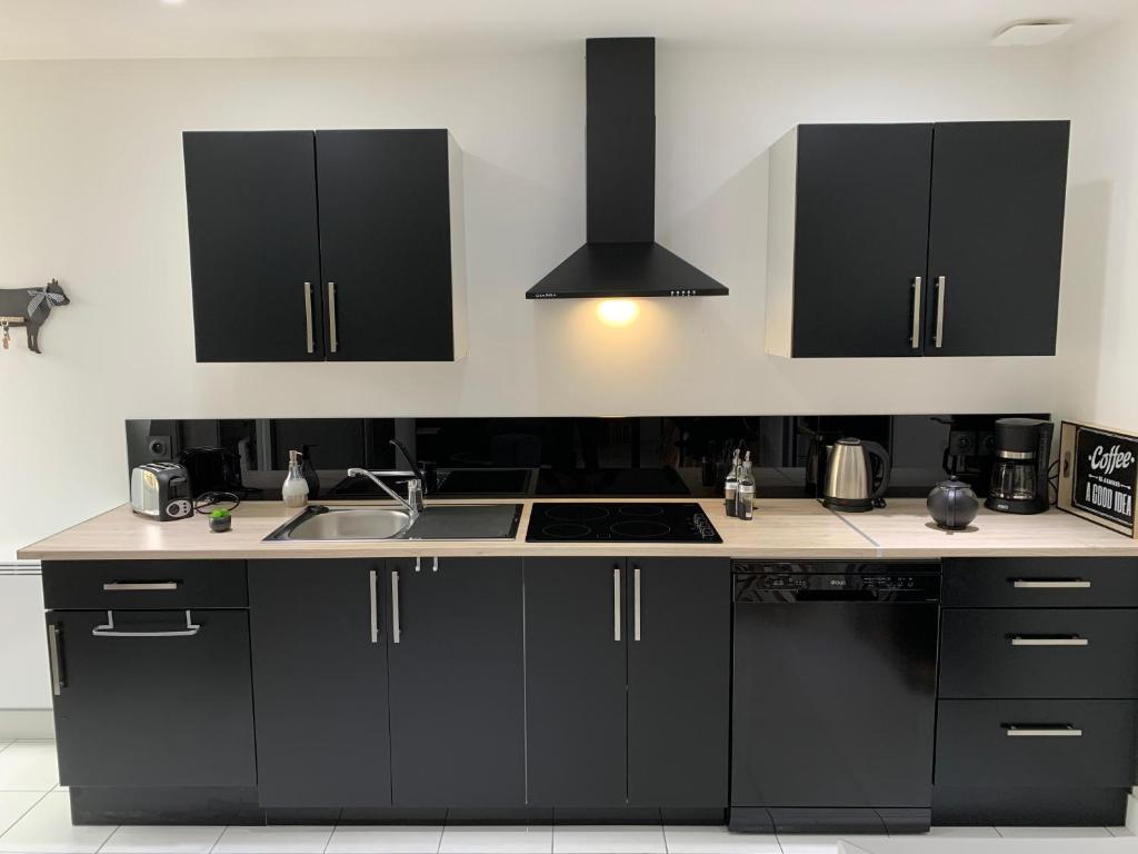 a kitchen with black cabinets and a sink at Gîte avec jardin à 1,5 km des plages du débarquement in Tracy-sur-Mer